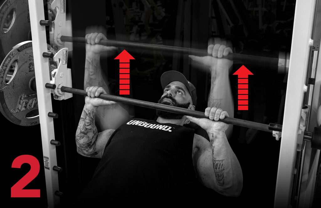 Steven Mitropoulous doing an incline smith machine bench press while wearing an Unbound Spplements t-shirt