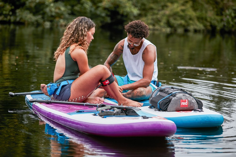 Man and Woman Sat on Ride MSL Paddle Boards in the middle of a lake