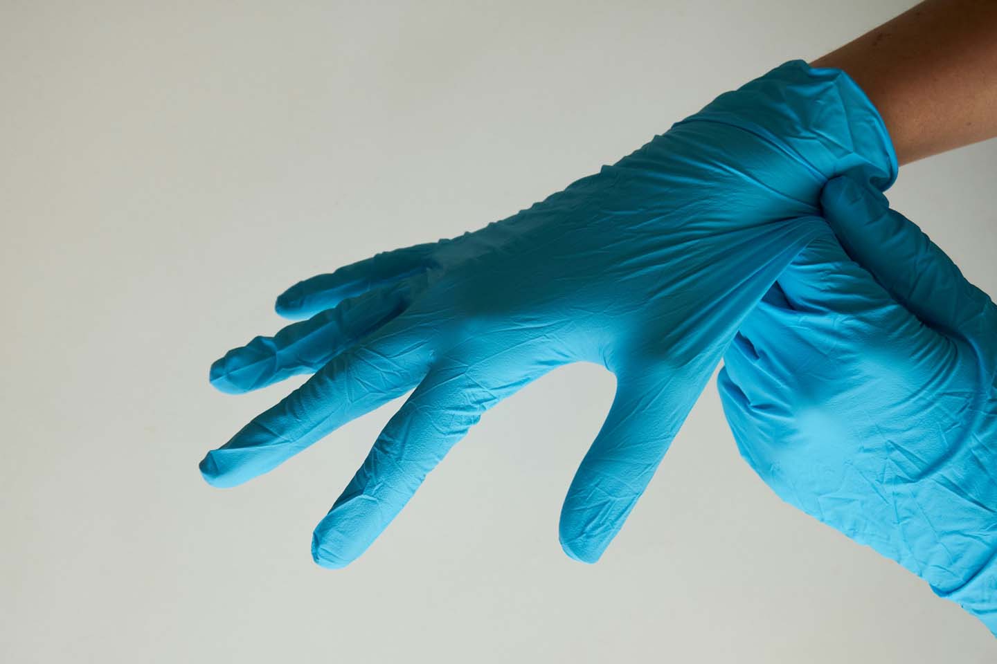 hands pulling on blue disposable gloves