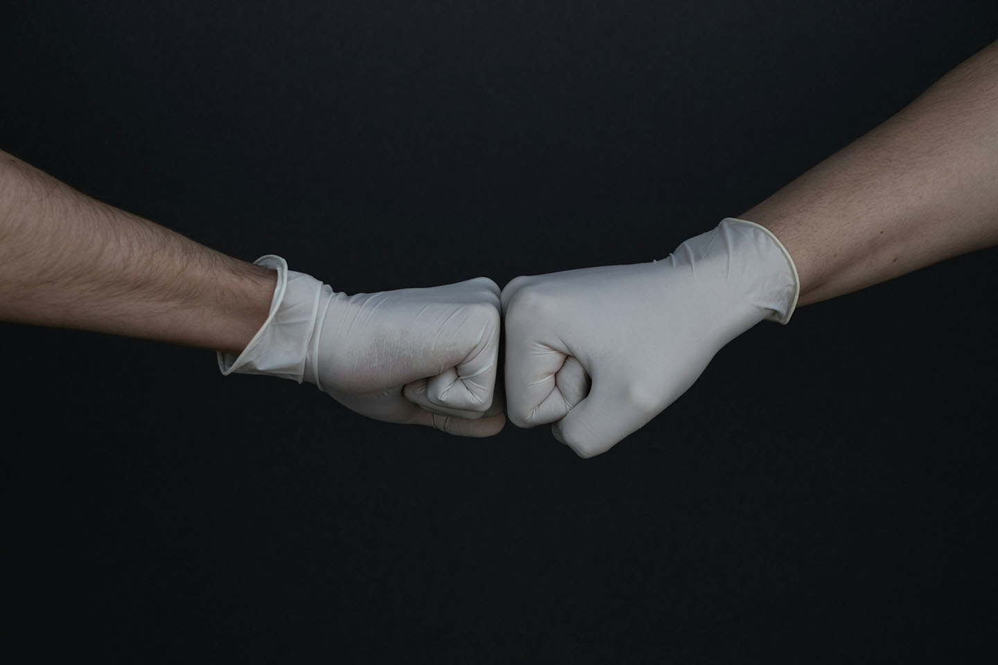 A pair of gloved hands performing the gesture known as fist-bumping.
