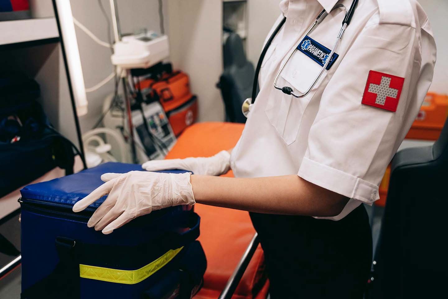 A paramedic wearing white gloves and holding a first aid bag