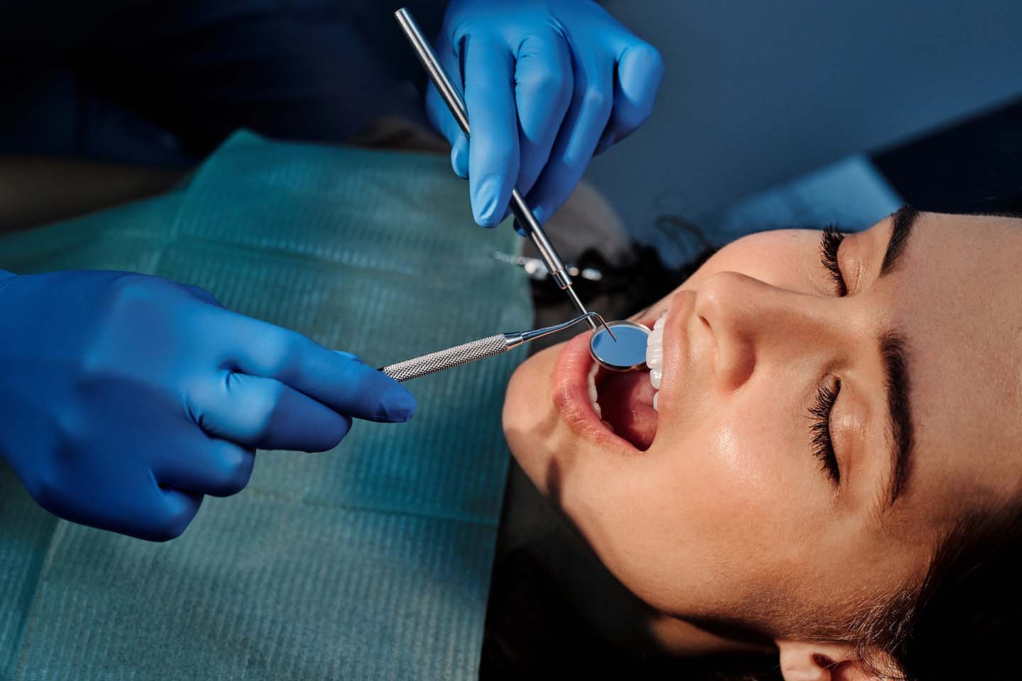 Dentist in blue gloves working in patient's mouth