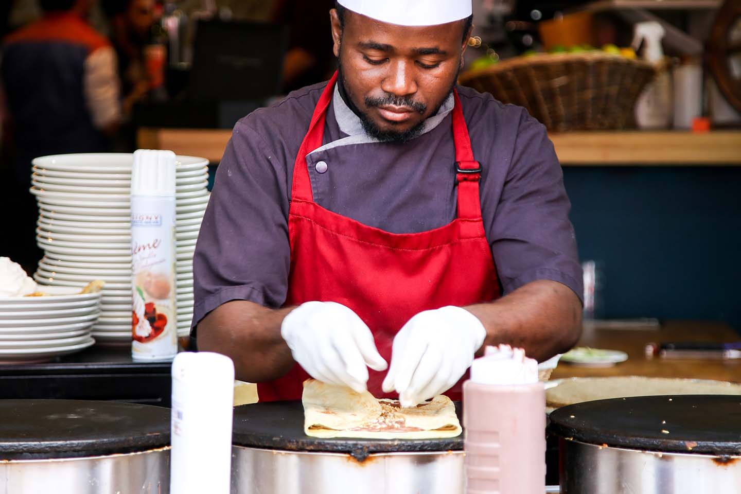 a chef wearing white gloves while cooking a roti