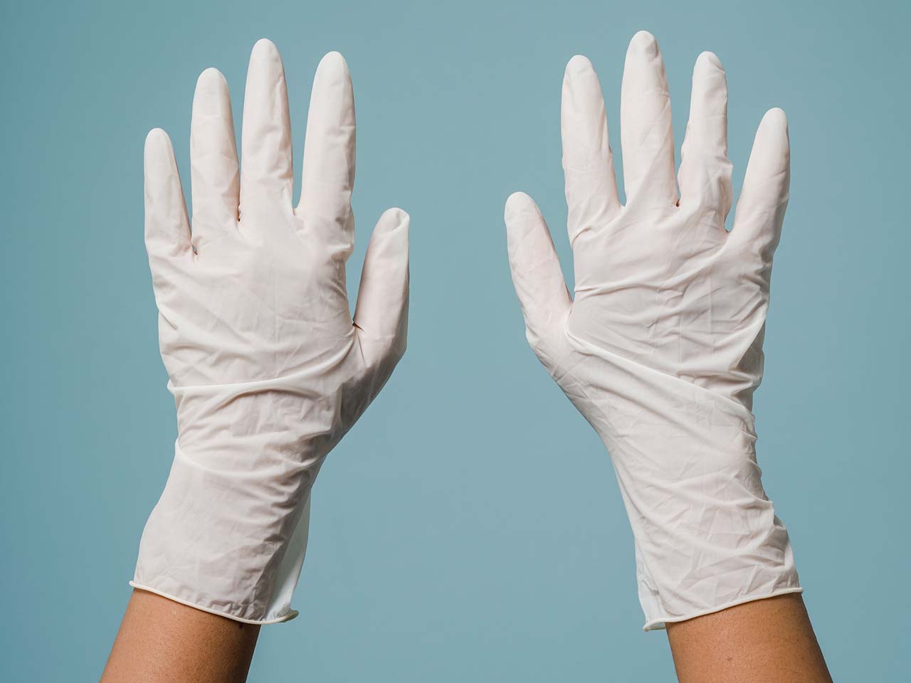 hands of a person wearing white gloves on a blue green background