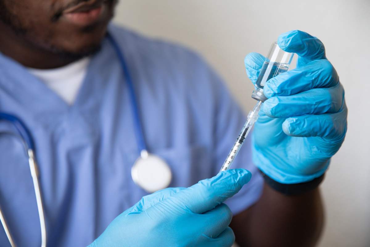 a doctor drawing a medicine out of a vial while wearing non-sterile gloves