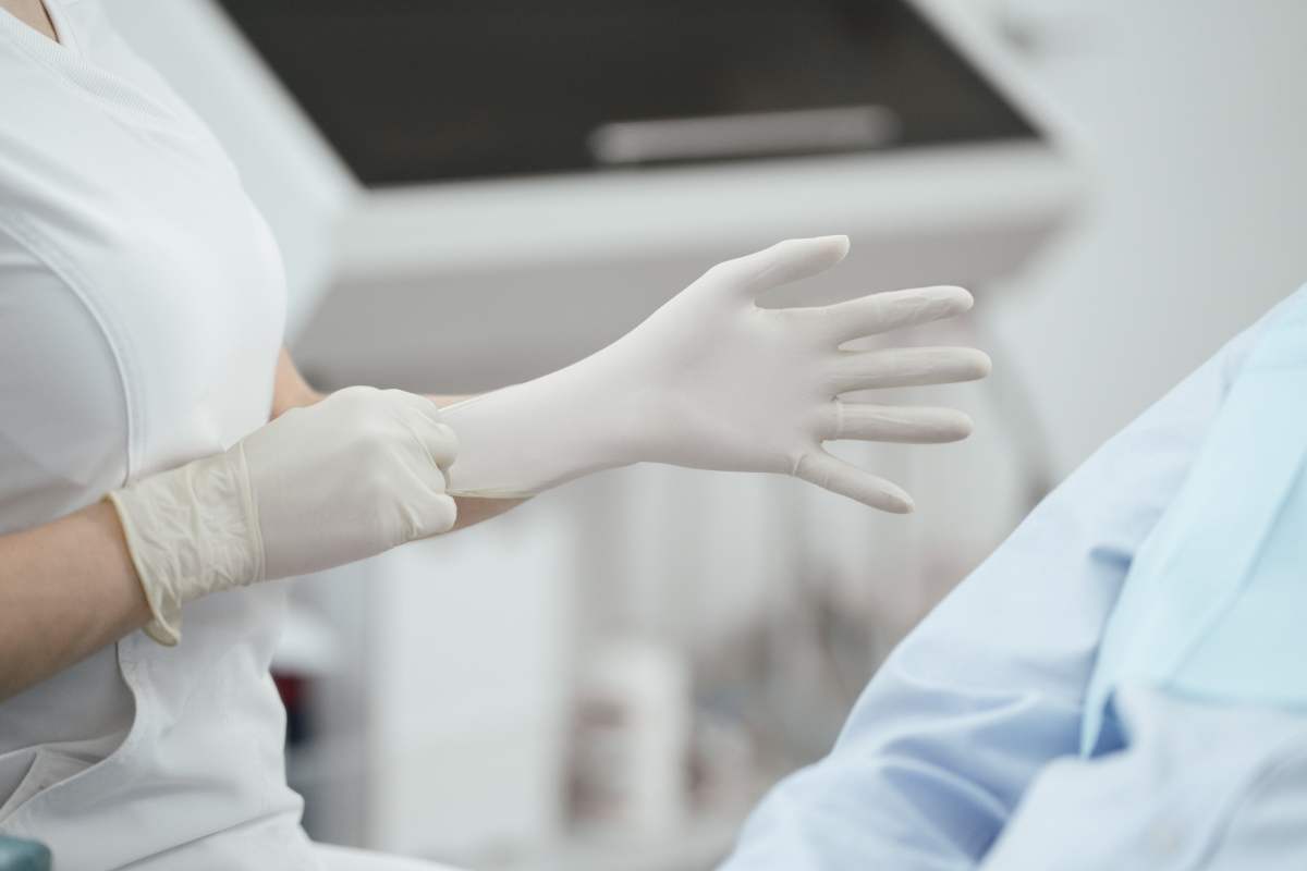 a medical professional donning a pair of white medical gloves