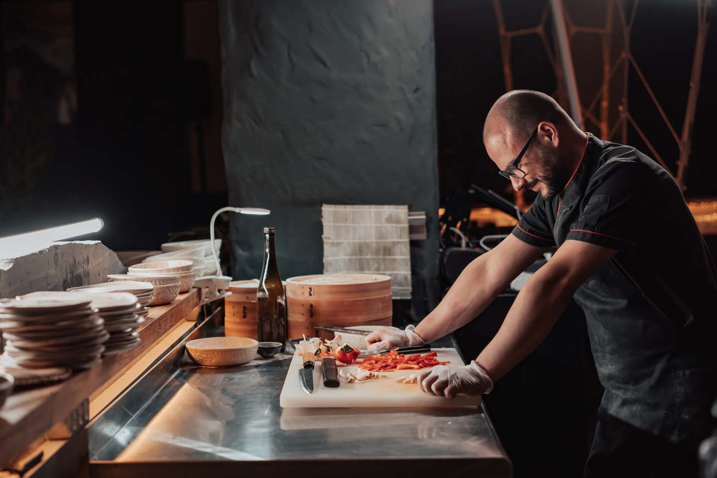 a man in black chef uniform standing by the chopping board