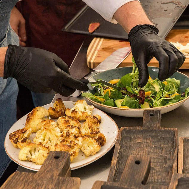 person wearing black gloves while preparing food