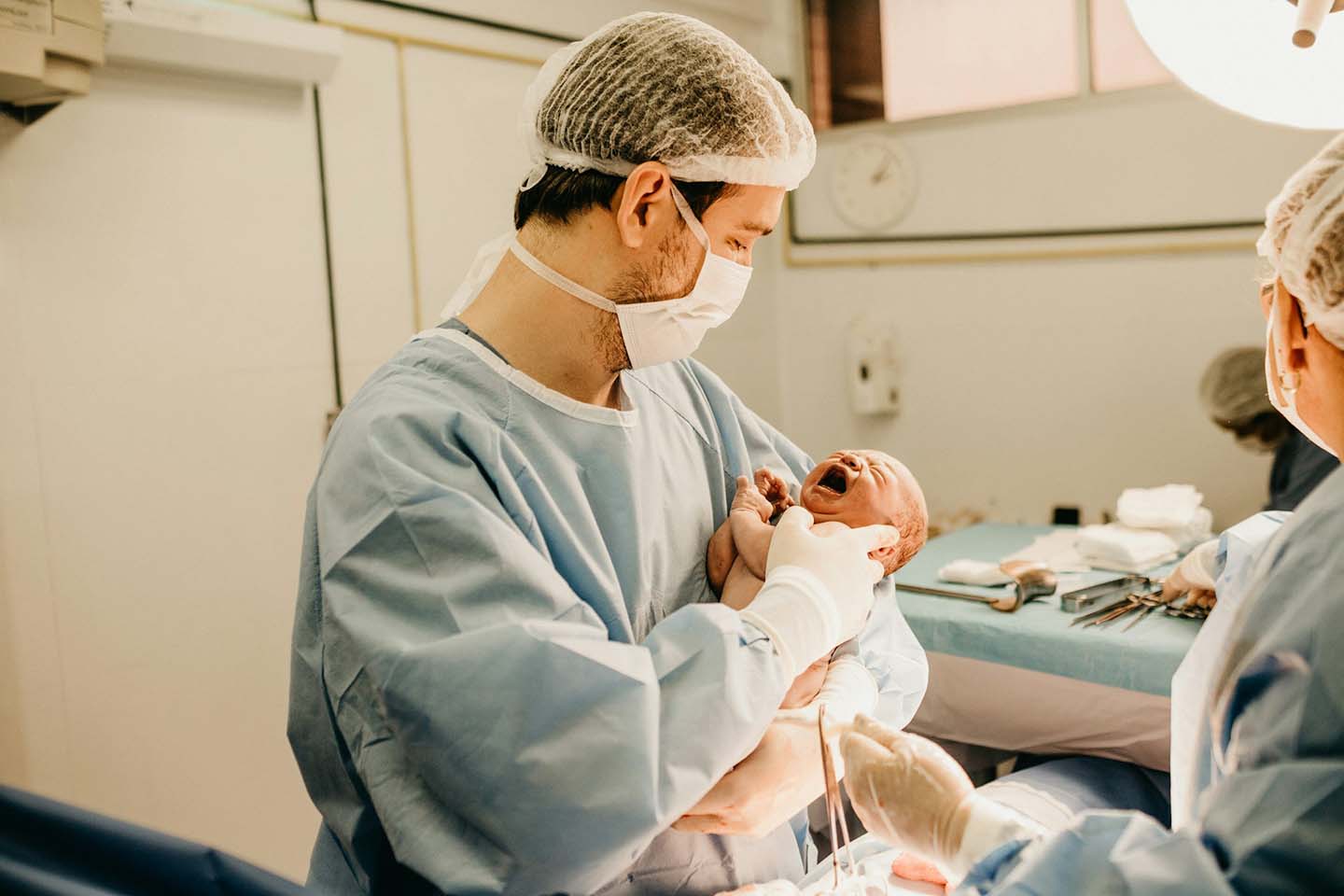 an obstetrician carrying a newborn in the delivery room