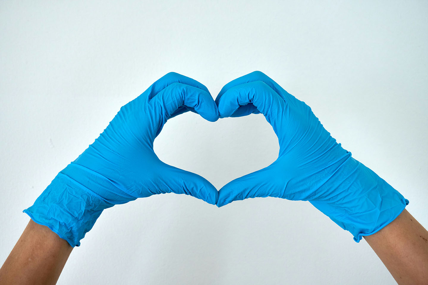 Hands wearing blue gloves form a heart