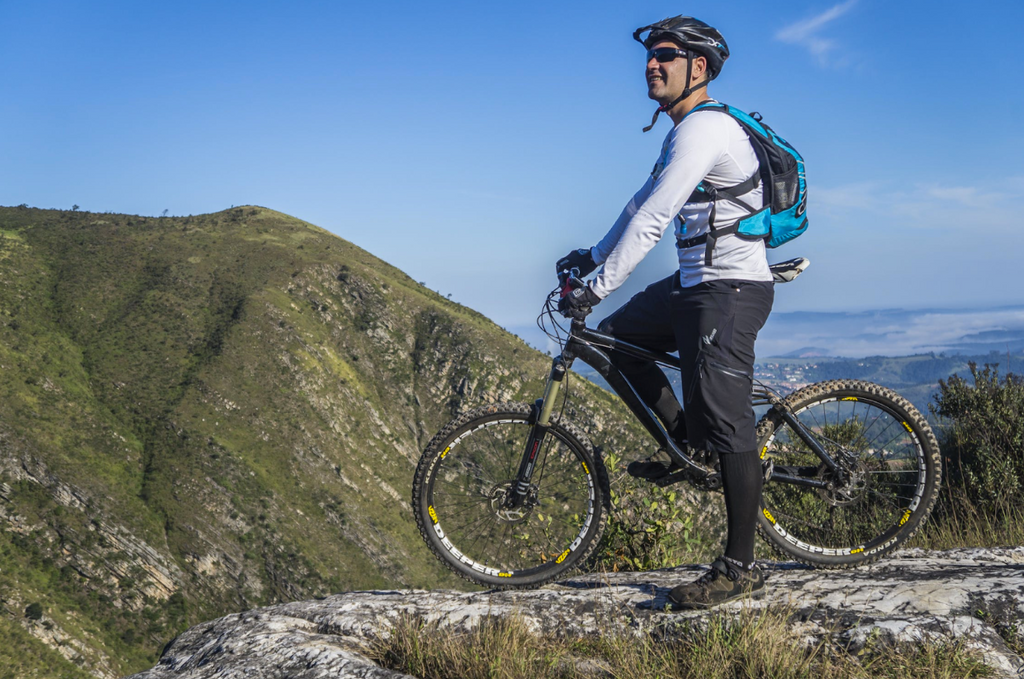 man on bike on top of mountain wearing cycling clothing and helmet
