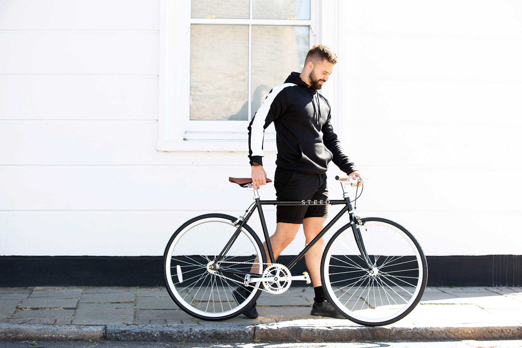Man in sportwear walking with black single speed fixie bike Steed Bike