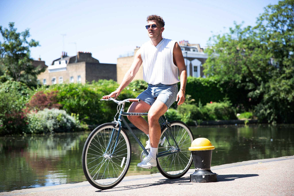 Boy in jean shorts and white top on blue Steed Bike next to canal