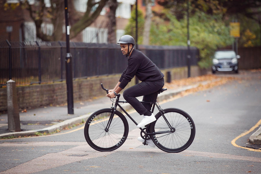 man cycling black Stallion Steed Bike with helmet on