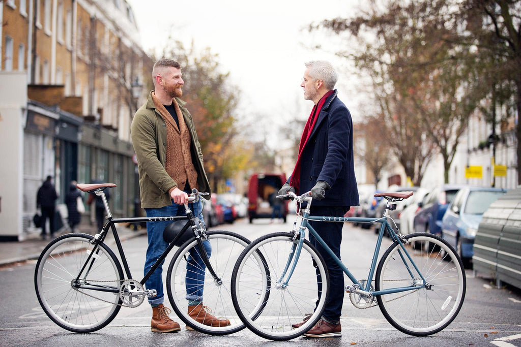 two men facing each other holding their Steed Bikes