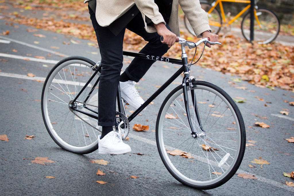 Man riding Onyx black Steed Bike with autumn leaves in background