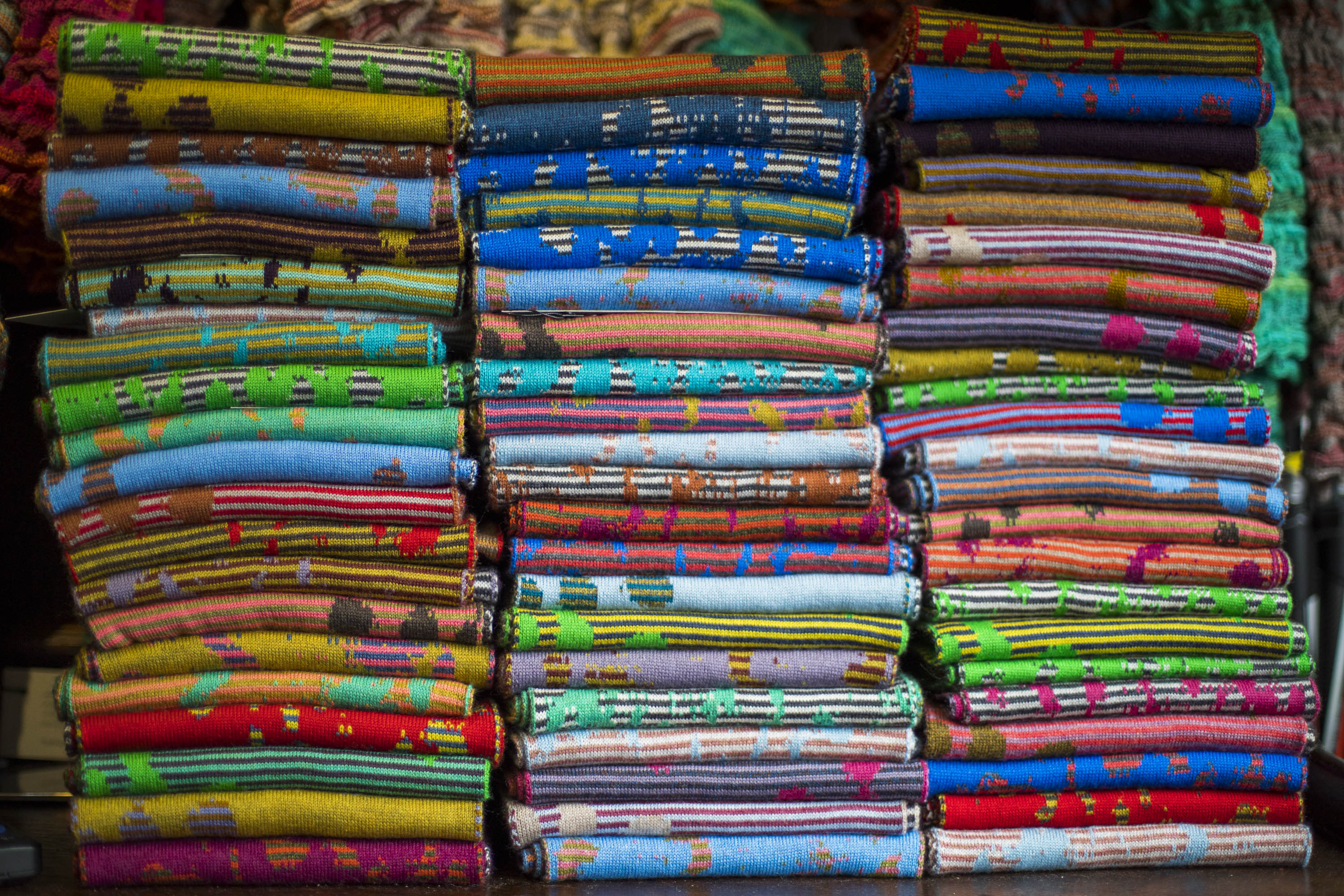 three tall stacks of marlet fine merino wool scarves. abstract patterns and many different colourways. in the Nielanell studio in Hoswick, Shetland