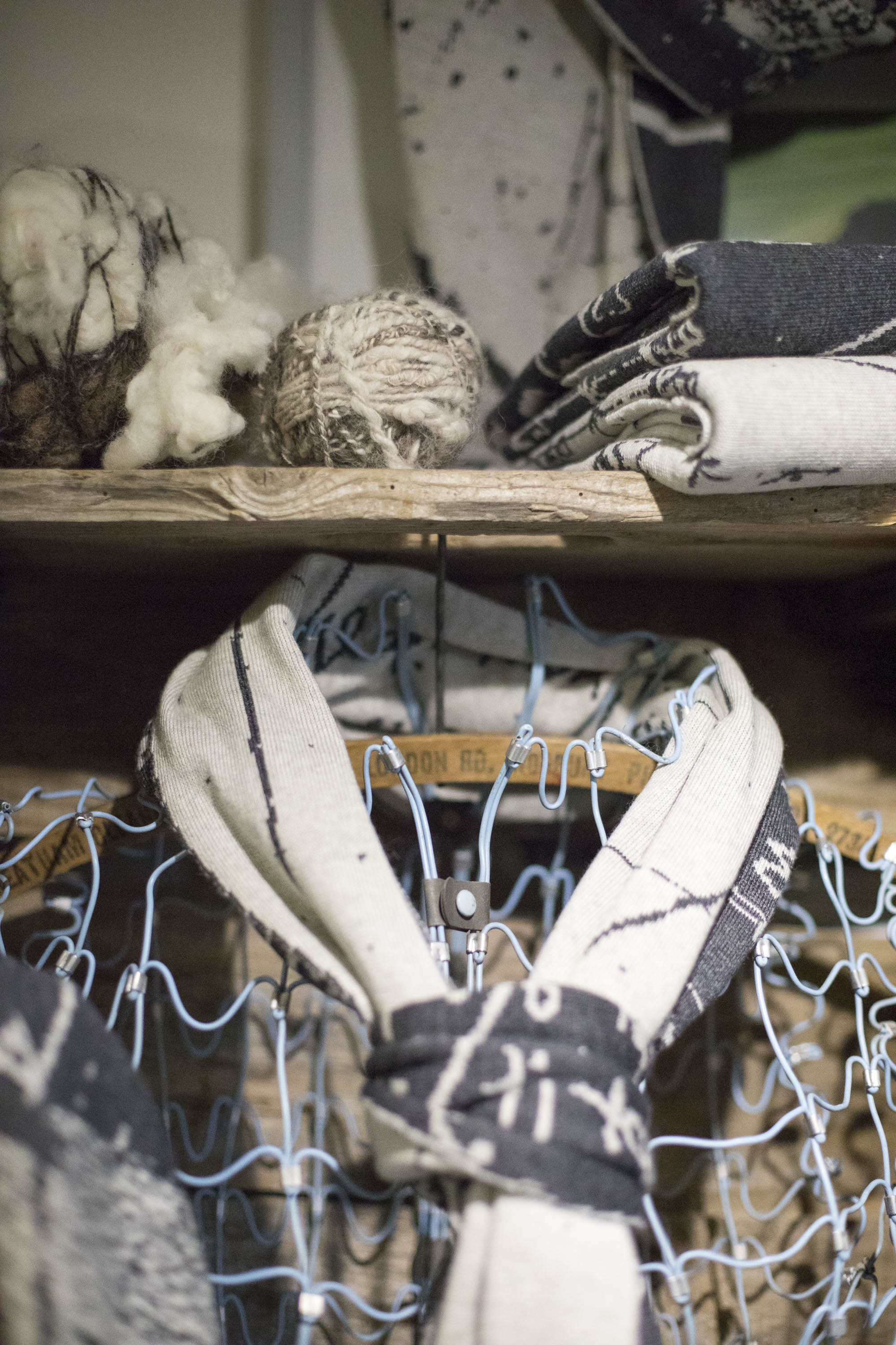Contemporary knitwear studio in the Shetland Islands, Scotland. Handspun yarn, a charcoal and stone white scarf on a wire frame mannequin, rustic shelving