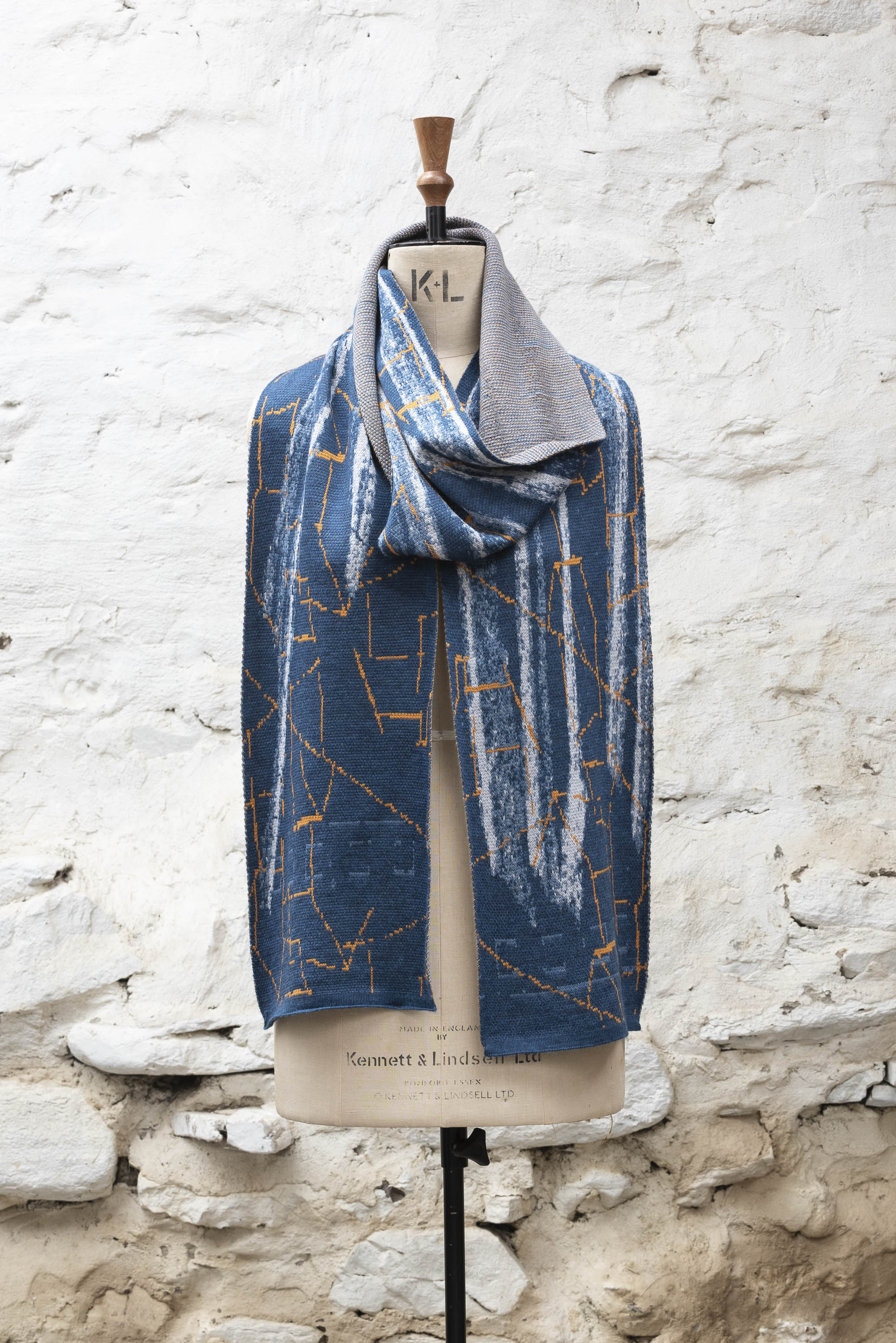 Contemporary Shetland knitted scarf in abstract design of blues and greys with orange highlights