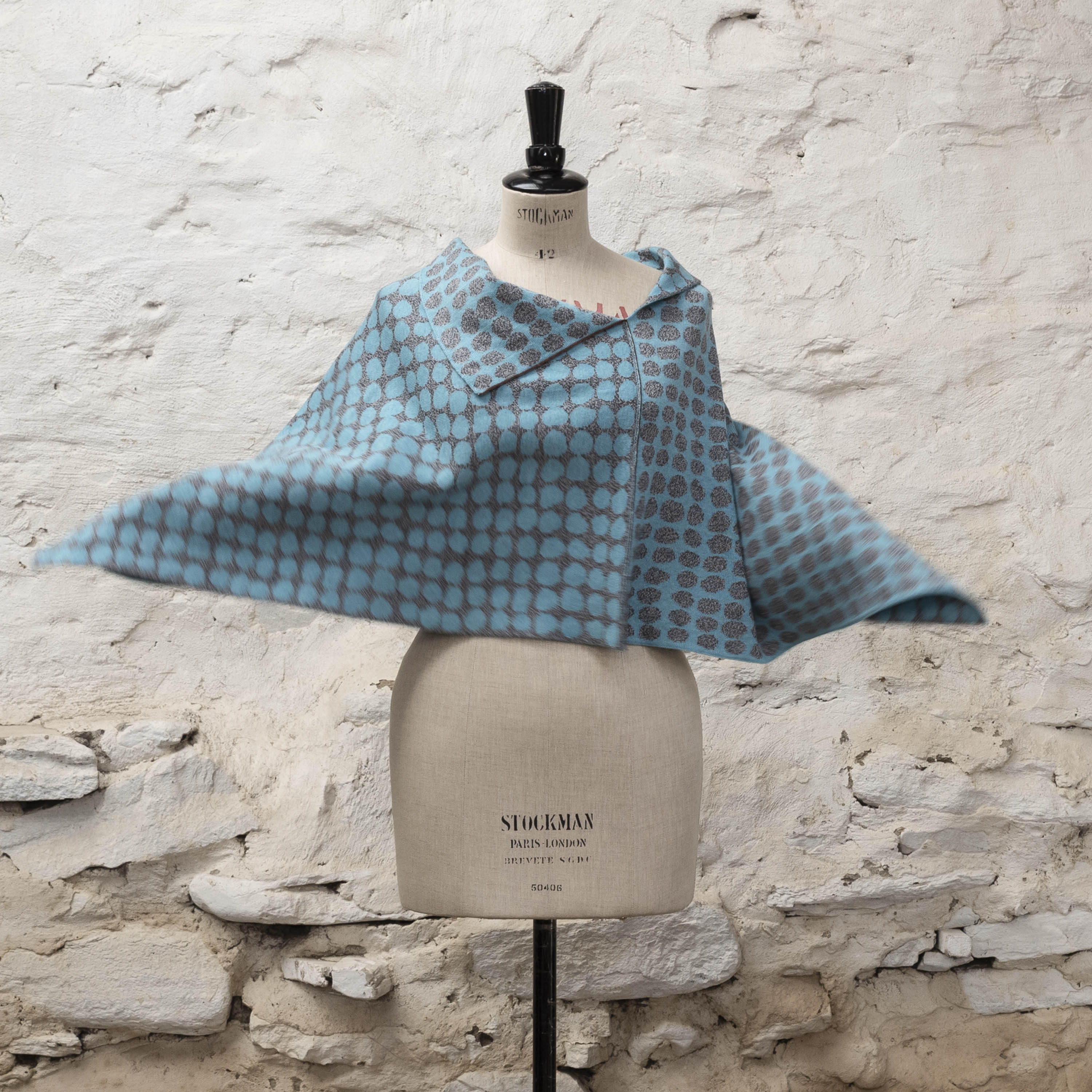 Layering knitwear - an irregular dot pattern in turquoise and marl grey in a knitted cape, made in Shetland. Shown on a vintage mannequin.