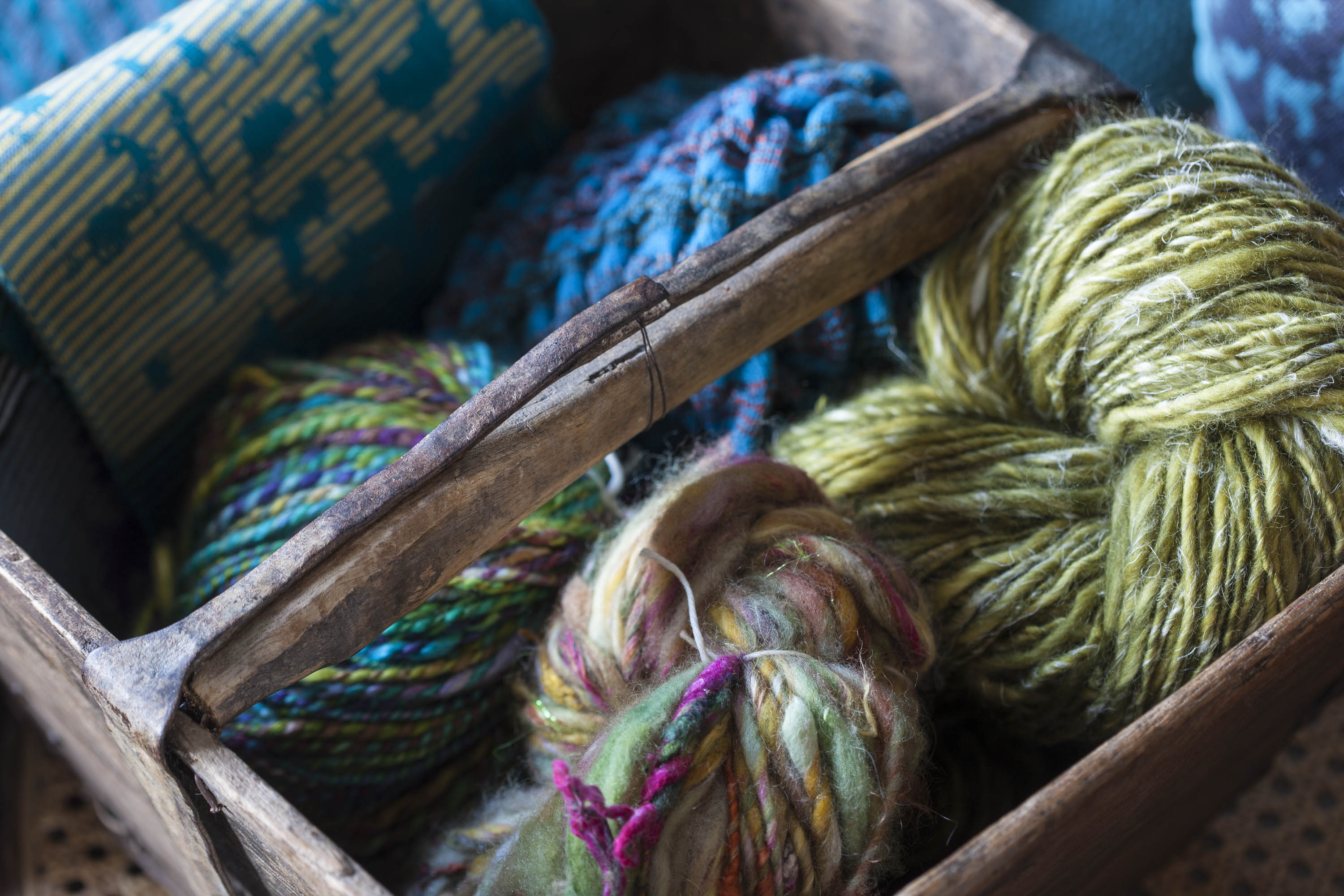 Handspun, chunky art yarn in several colours in a wooden trug at the Nielanell knitwear studio in Hoswick, Shetland.