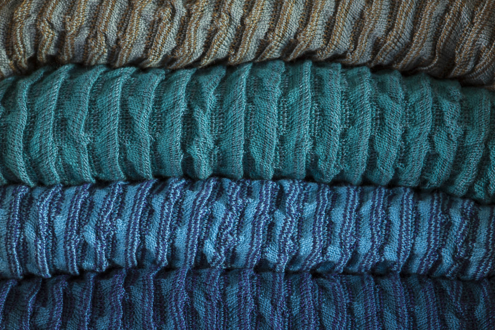 Close up detail of a stack of rigg jackets, in several different colours. You can see the ridged colour and stripe.