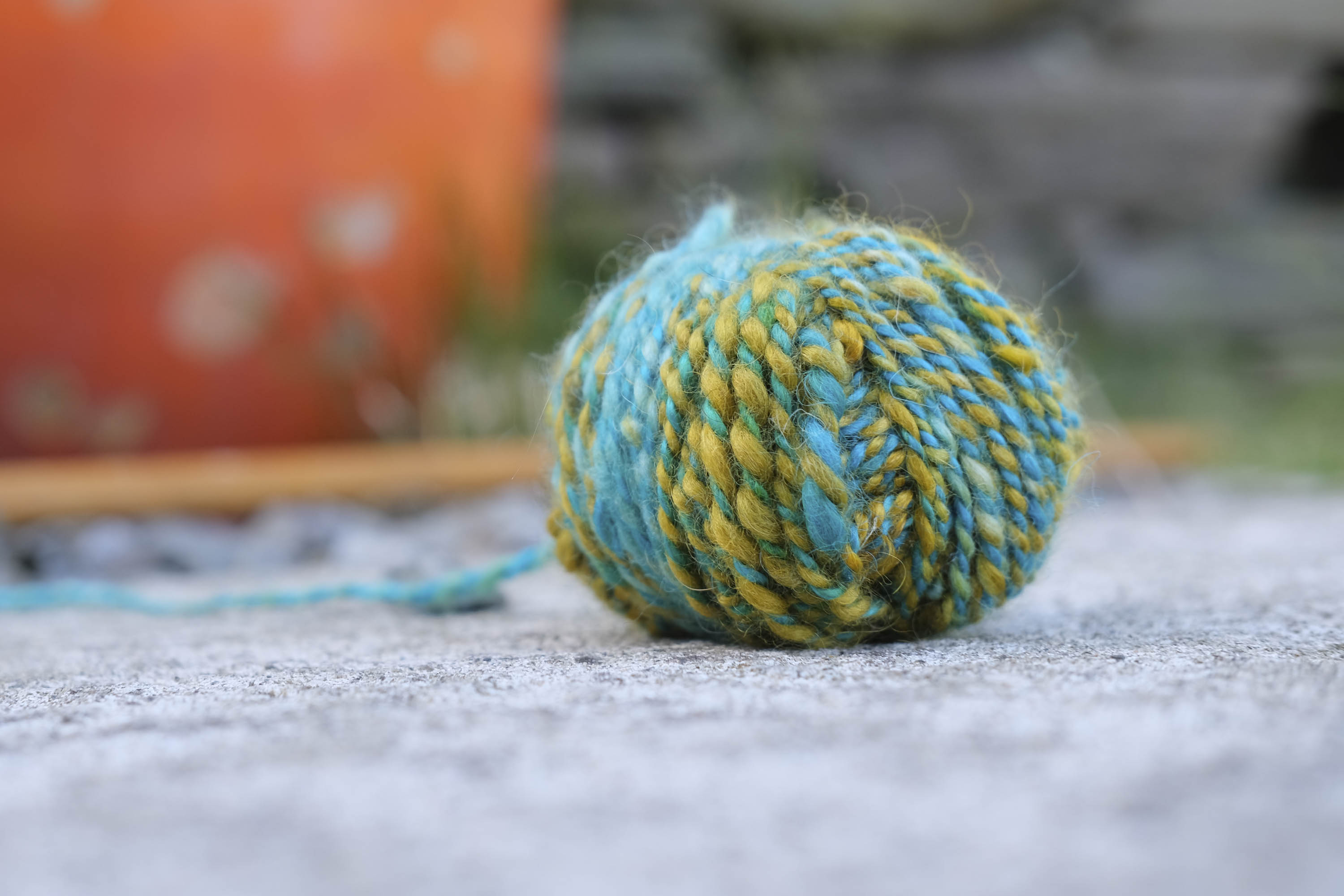 Ball of handspun, hand-dyed yarn in yellows, greens and turquoise in two ply