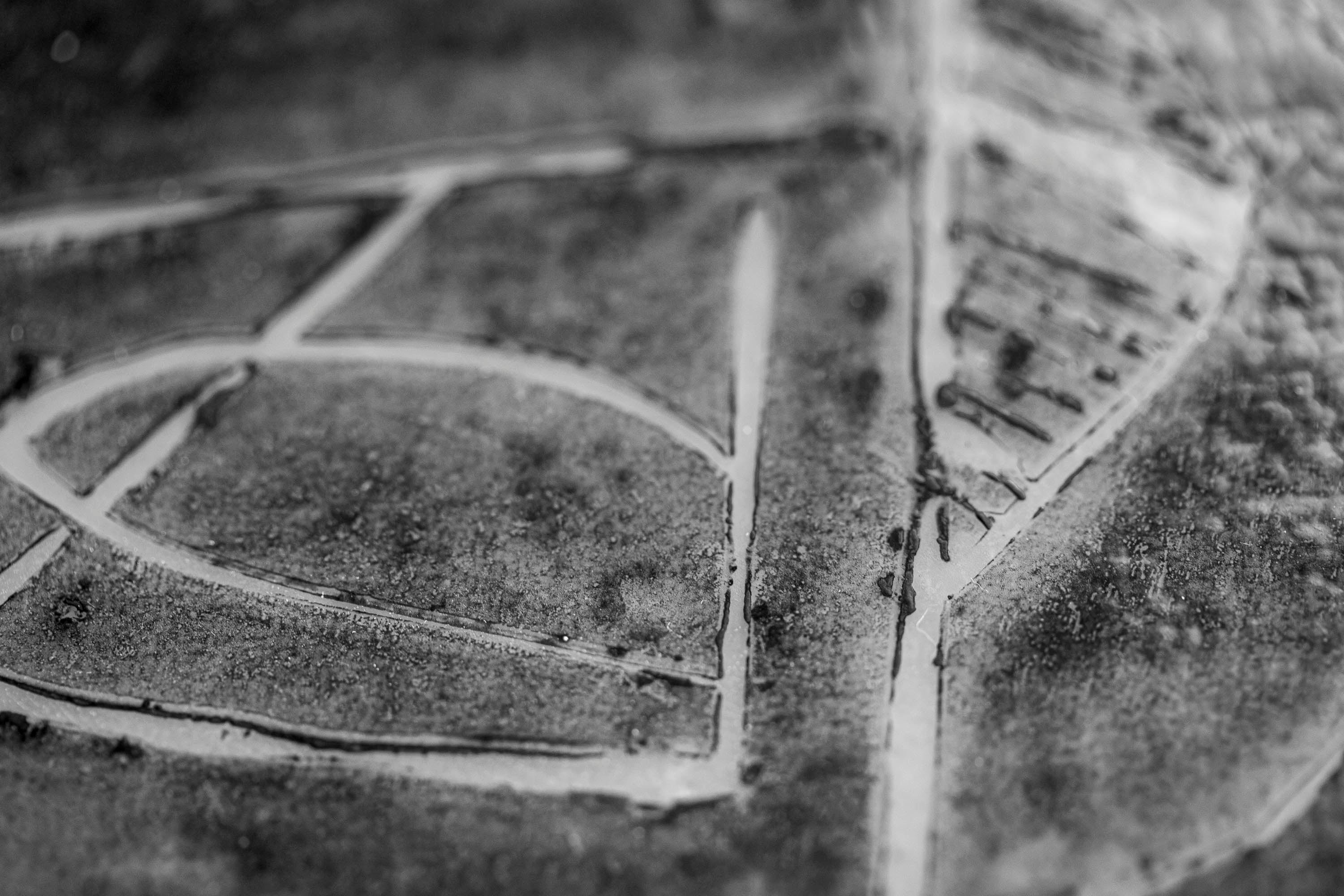 Close up detail of a lino cut printed onto glass. In the black and white photograph the texture of the ink is seen. The print is an abstract, curvilinear motif