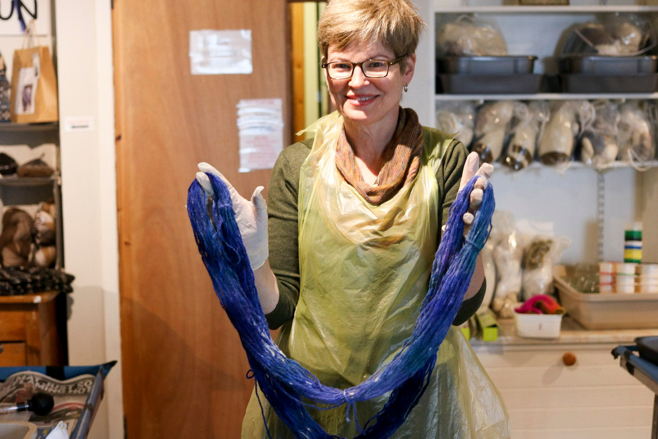 A woman holds a hank of hand-dyed indigo yarn in Hoswick, Shetland