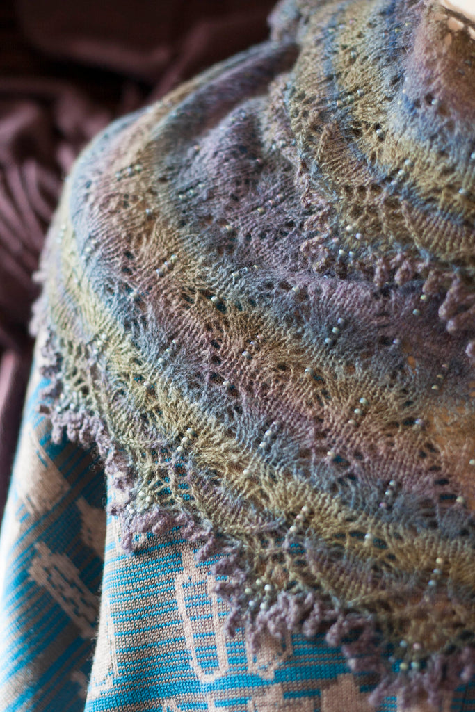 Fine shetland-style lace shawl knitted in hand-dyed, handspun yarn. In soft purples and blues with some beads.