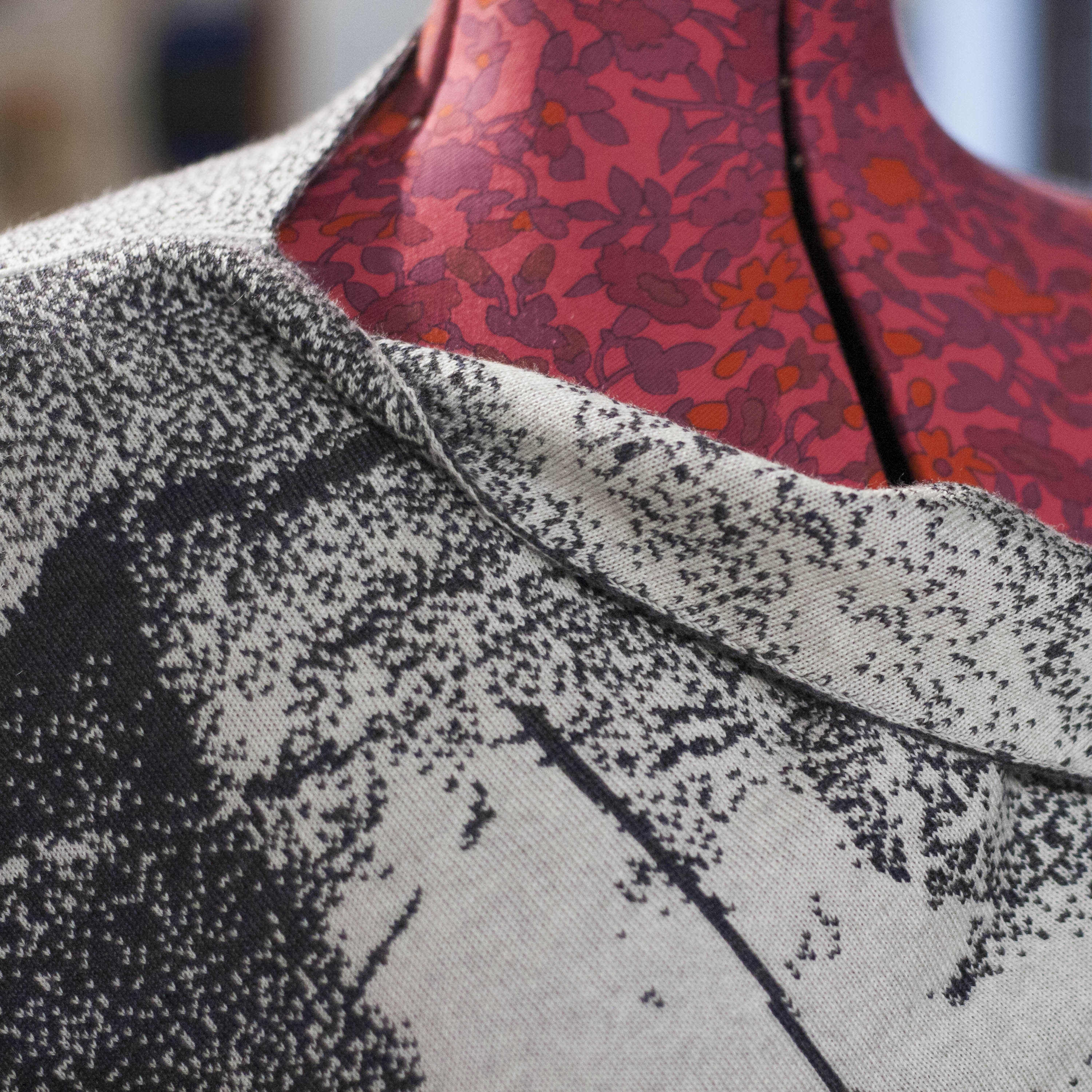 Detail of neckline on designer Scottish knitwear. A finely knitted cape with abstract grey and stone white patterning.