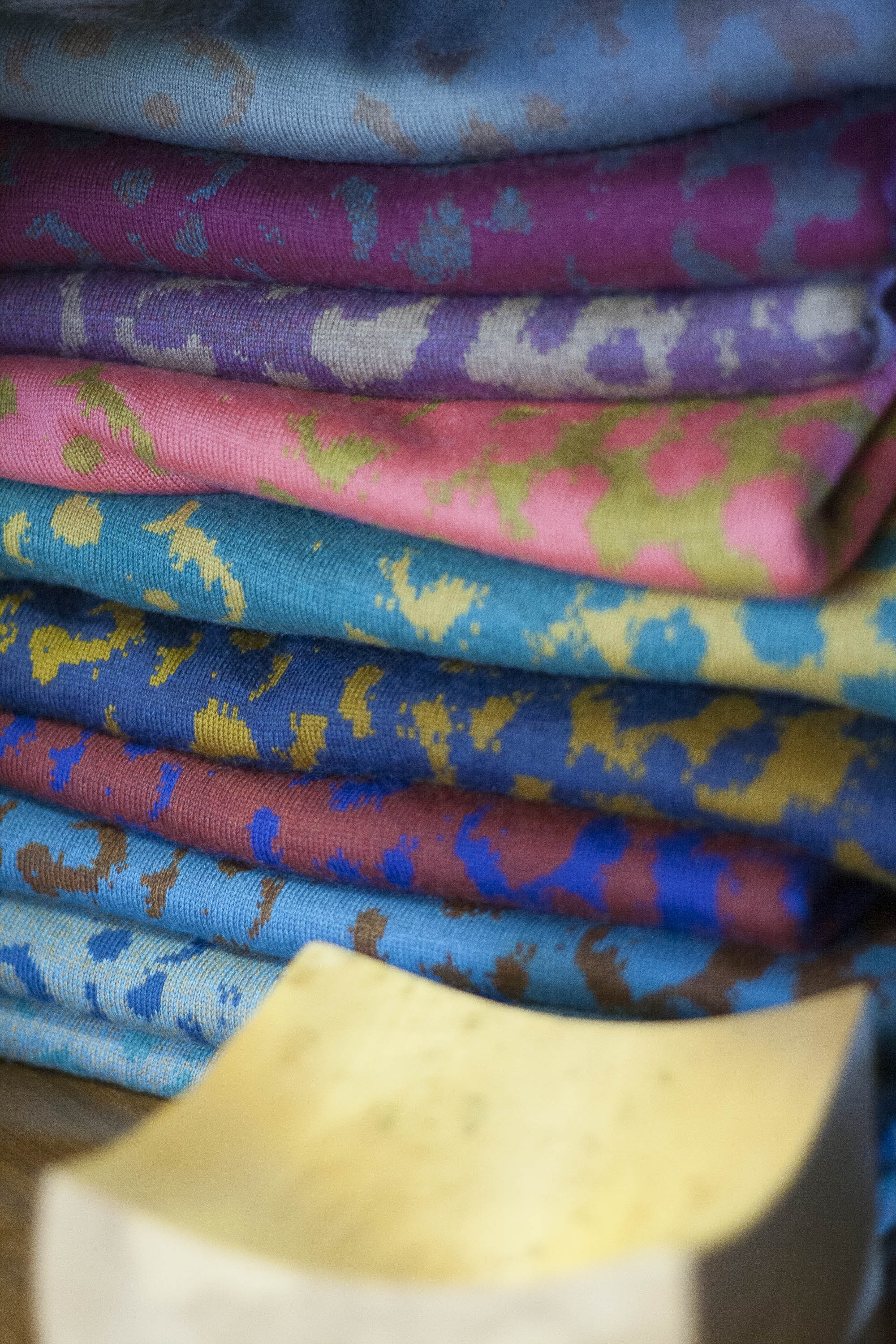 Stack of Marlet knitwear in several different colours. Wooden bowl in foreground.