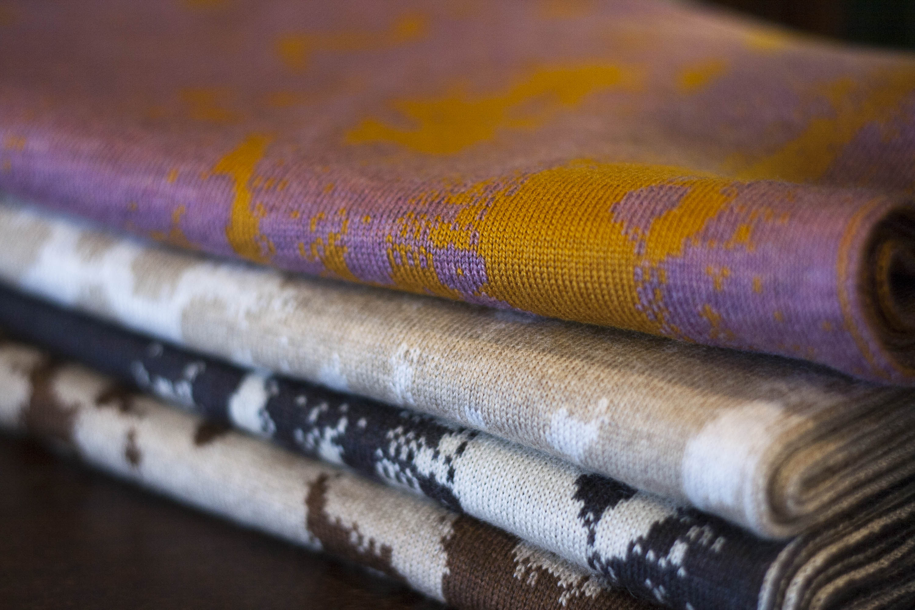 Stack of contemporary Scottish knitwear in extra fine merino wool, these are cowls in an abstract mottled pattern