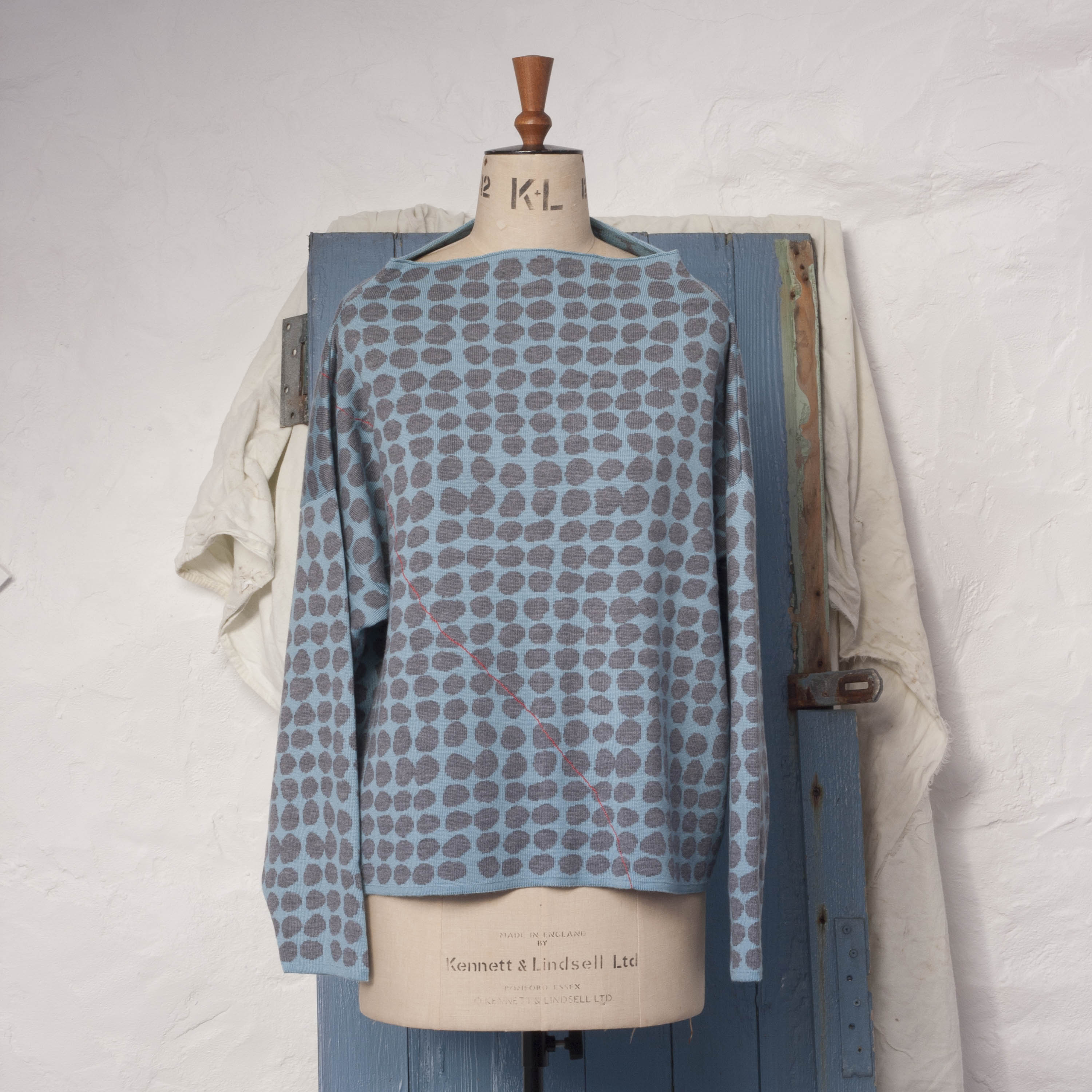 Ebb-stanes contemporary Scottish jumper. A pattern of pebbles in blue and marl, with coral individually drawn line