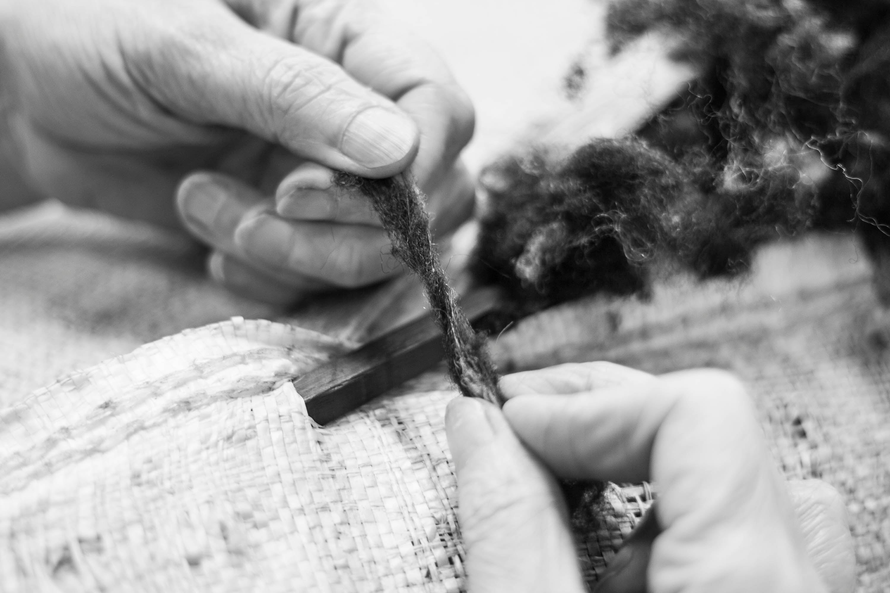 Close up of a worker's hands holding washed fleece at Jamieson's of Shetland mill - which is ready for spinning 