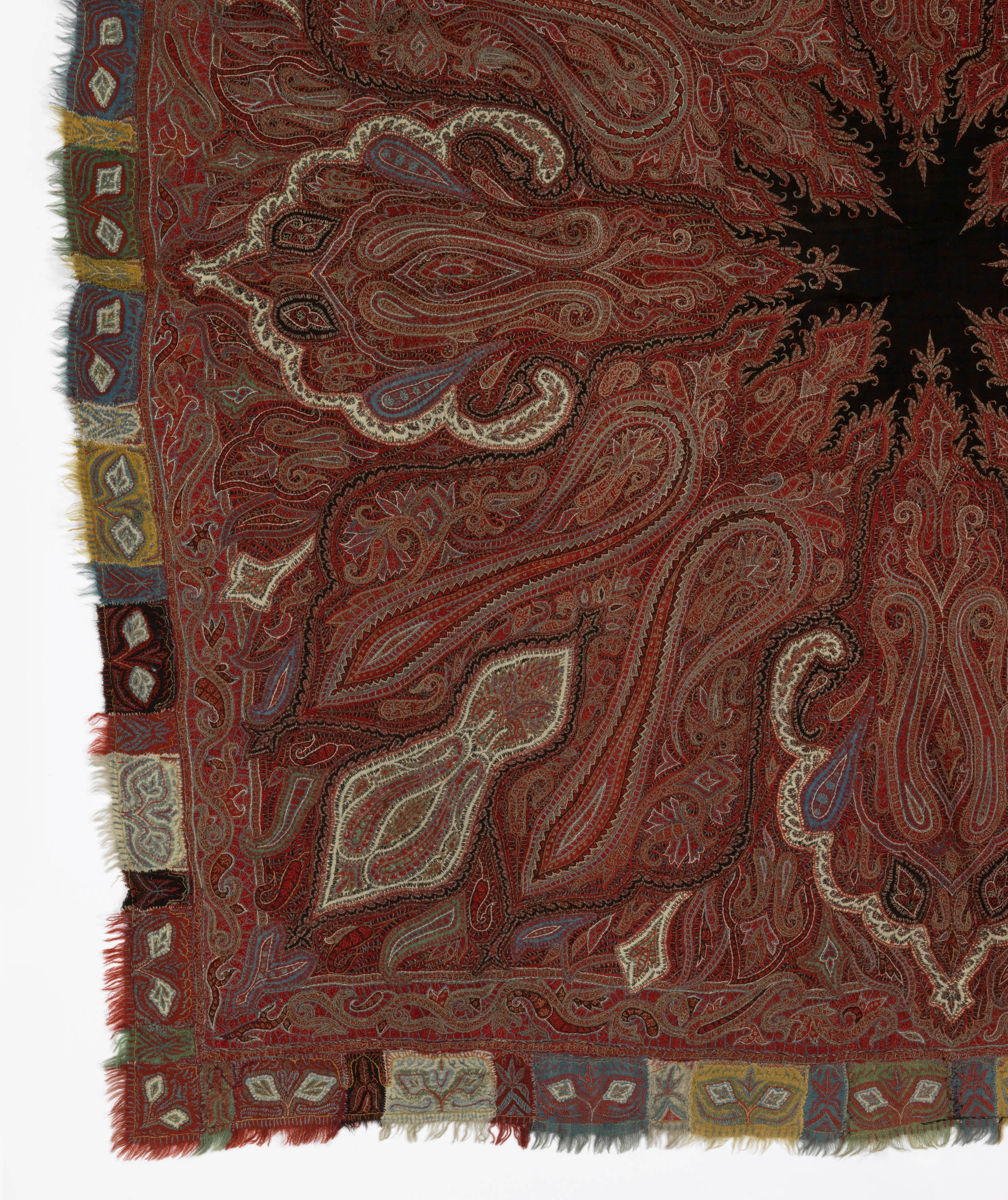 19th Century Kashmiri shawl in the collection of the Cooper Hewitt. Reds with cream areas, lozenge shapes, black star-shaped centre. Edging with various colour blocks