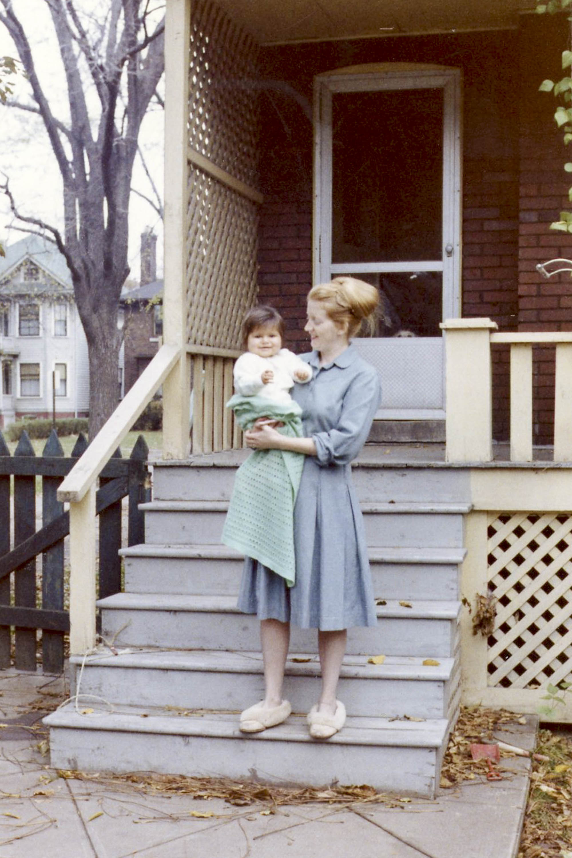 A woman and baby on the steps of a house in Canada. 1960s.