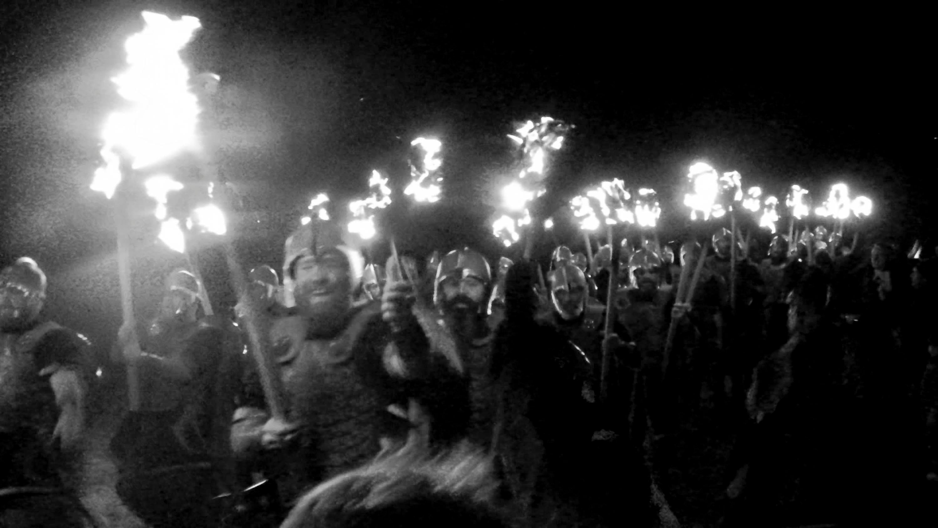 Guizers dressed as Vikings process holding torches at South Mainland Up Helly Aa - Smuha
