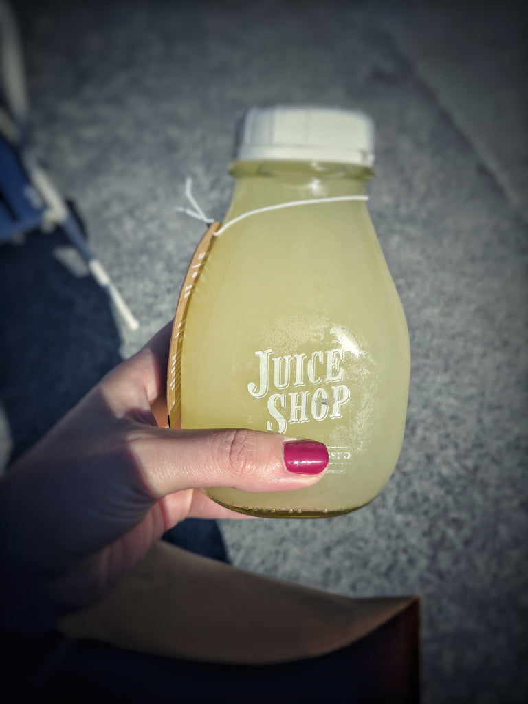 Hand holding a bottle of yellow juice