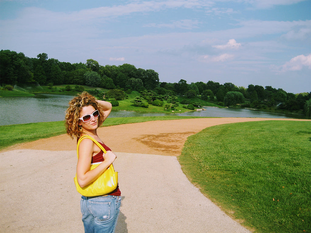 Adrianne at age 21 with a yellow purse, doing a goofy glamour shot outdoors