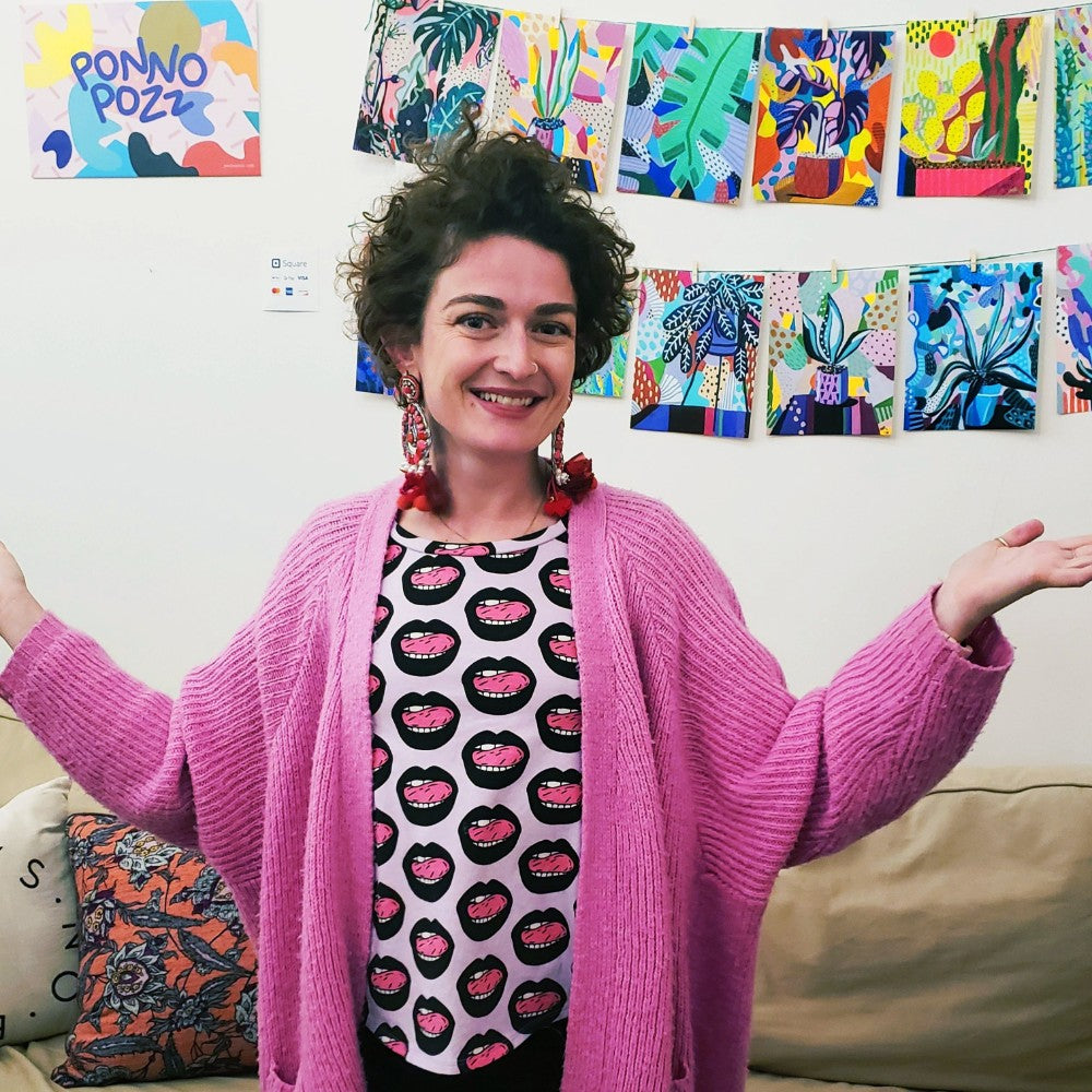 The artist smiles in front of her artwork