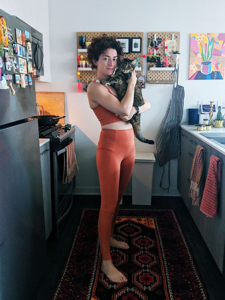 The artist holds her cat in the kitchen