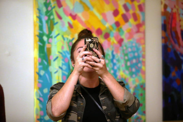 A customer takes a picture of the art with her phone