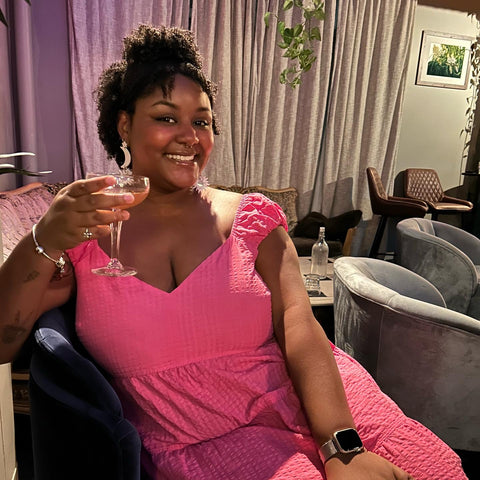 this is a photo of the me, the owner, Michaela. I'm holding a craft cocktail while wearing a pink dress!