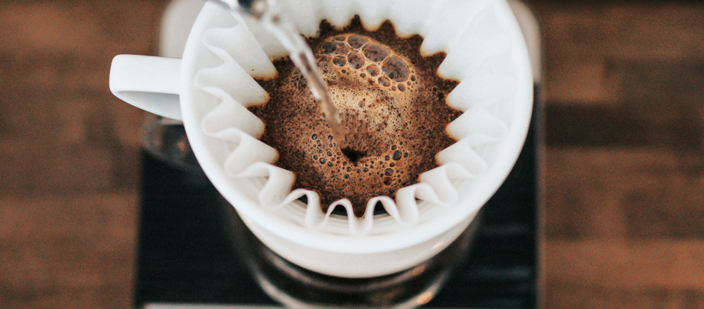 pouring hot water into a filter to make a pour over coffee at home