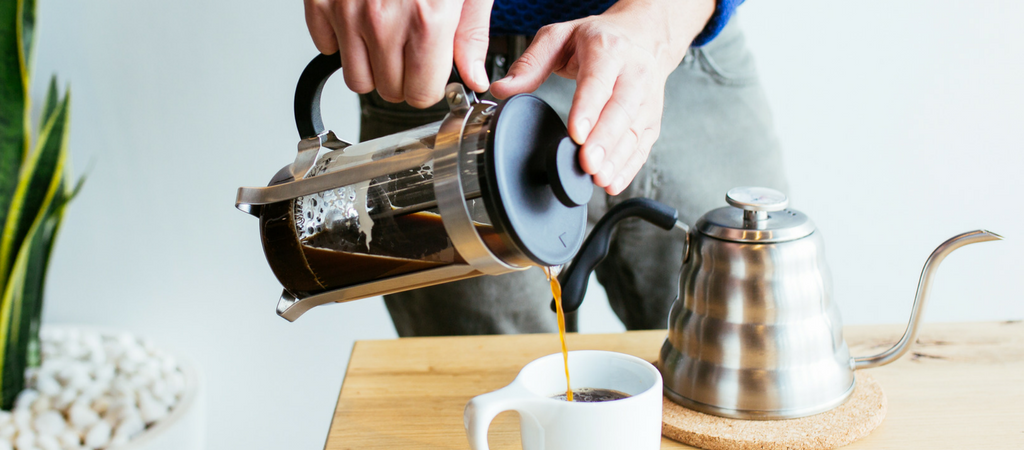 french press pouring into a cup with a kettle by the side