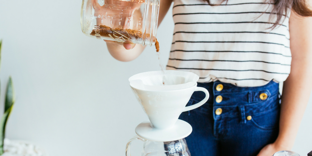 pouring coffee grinds into a hario v60 for the perfect brew by an expert