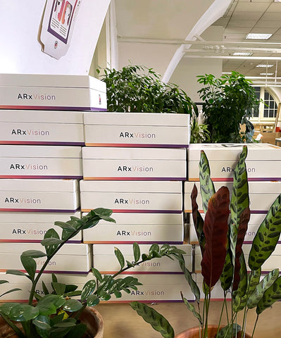 ARx packaging boxes stacked behind houseplants