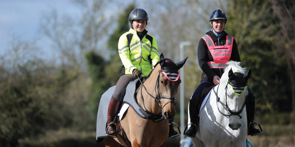 Two riders and horses wearing hi-viz
