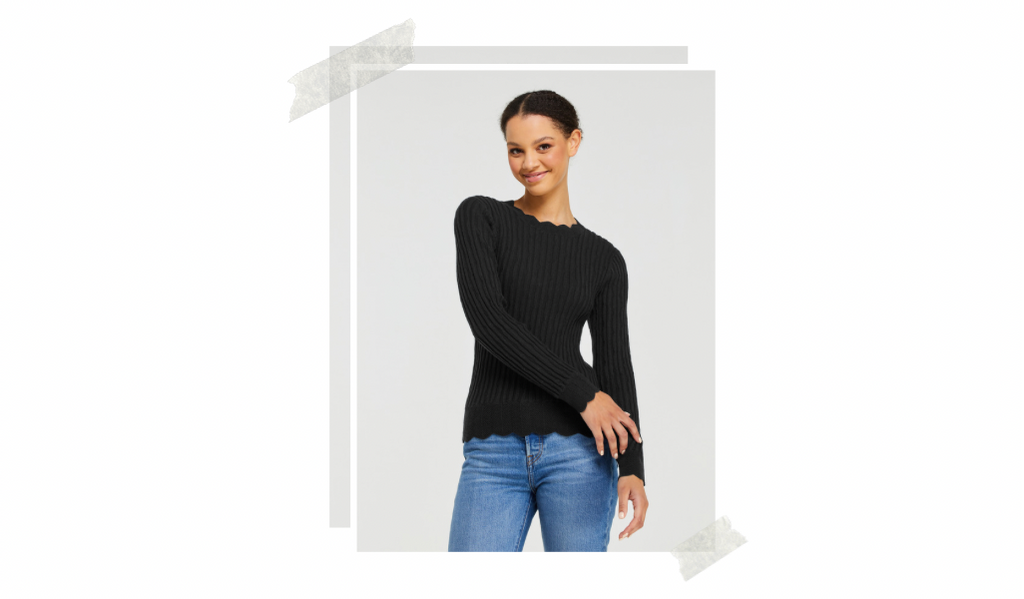 Model is standing posing with her arm swaying in front of her body and the other is straight by her side. She is wearing a black ribbed fitted knit top that has scalloped neckline, hem and sleeves.